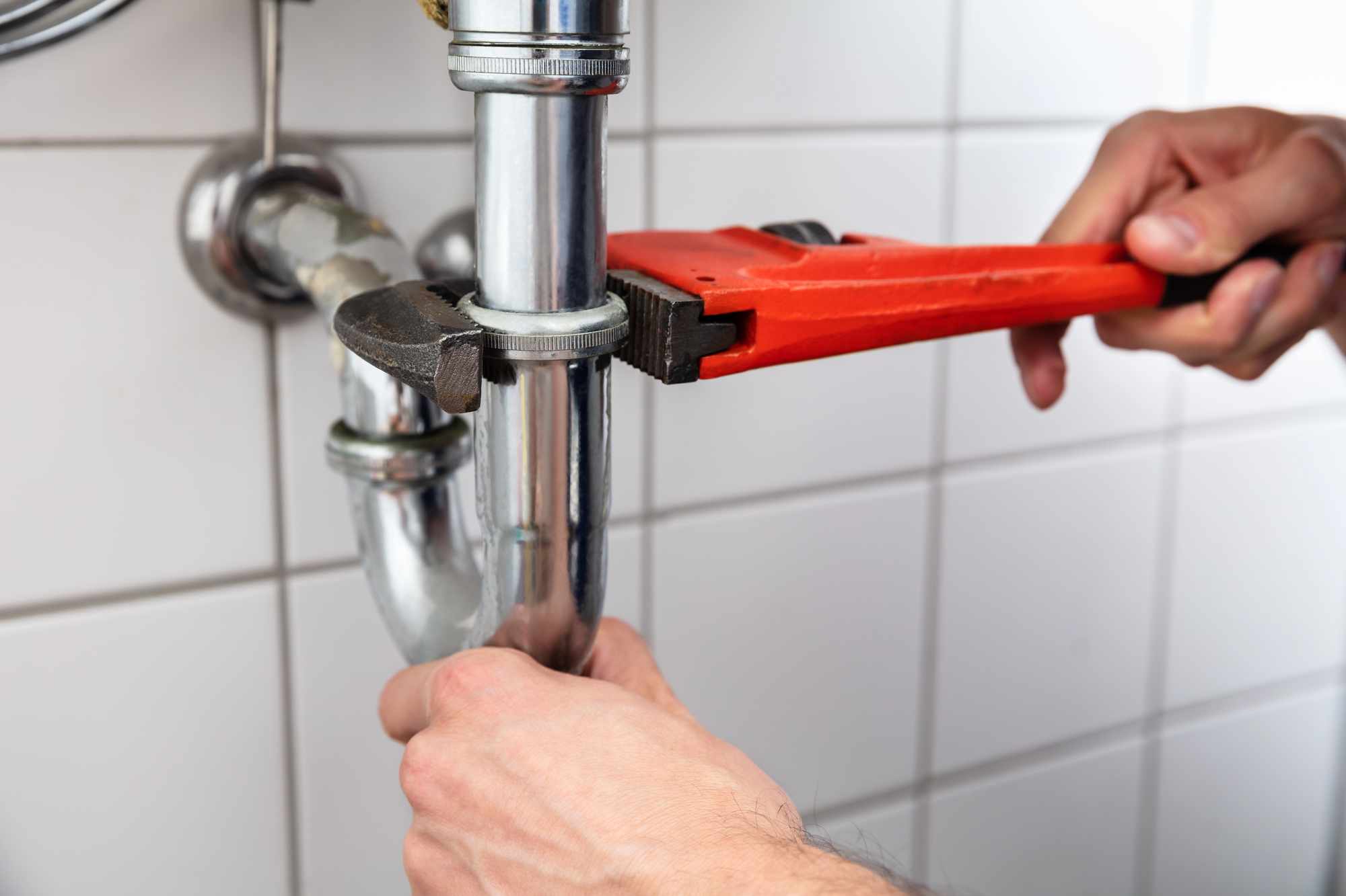 A plumber's hands adjusting a pipe.