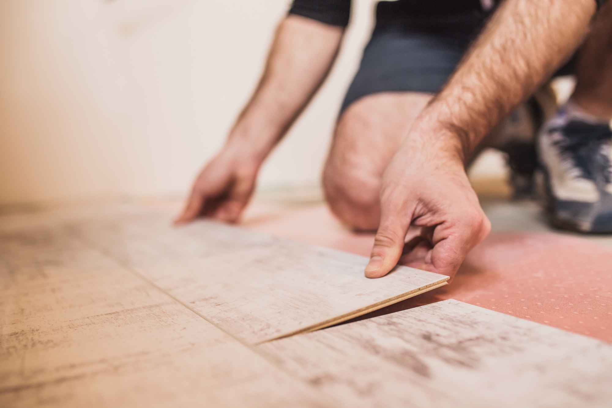 A flooring worker's hands connecting laminate panels.