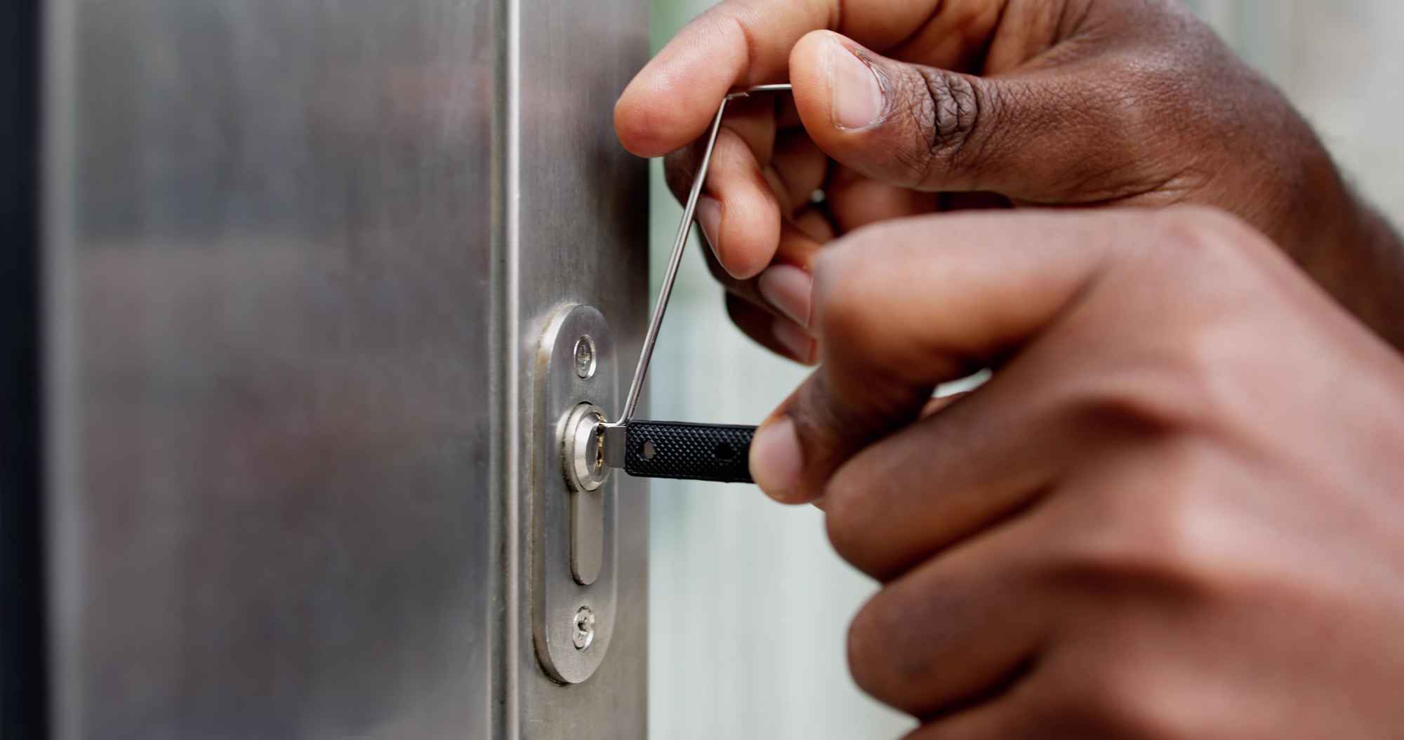 A locksmith's hands picking a lock.