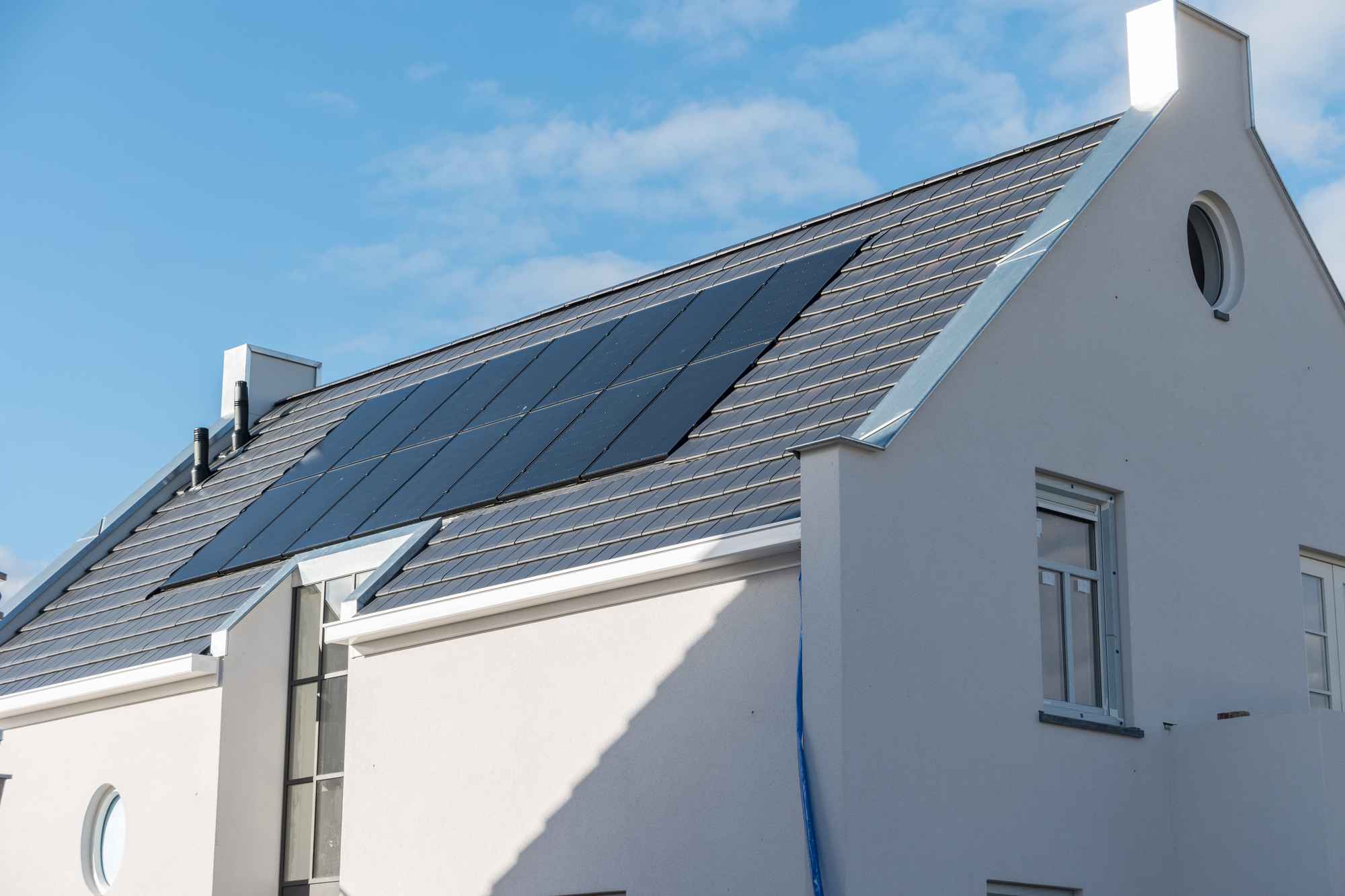 A solar panel installation on a white house on a sunny day.