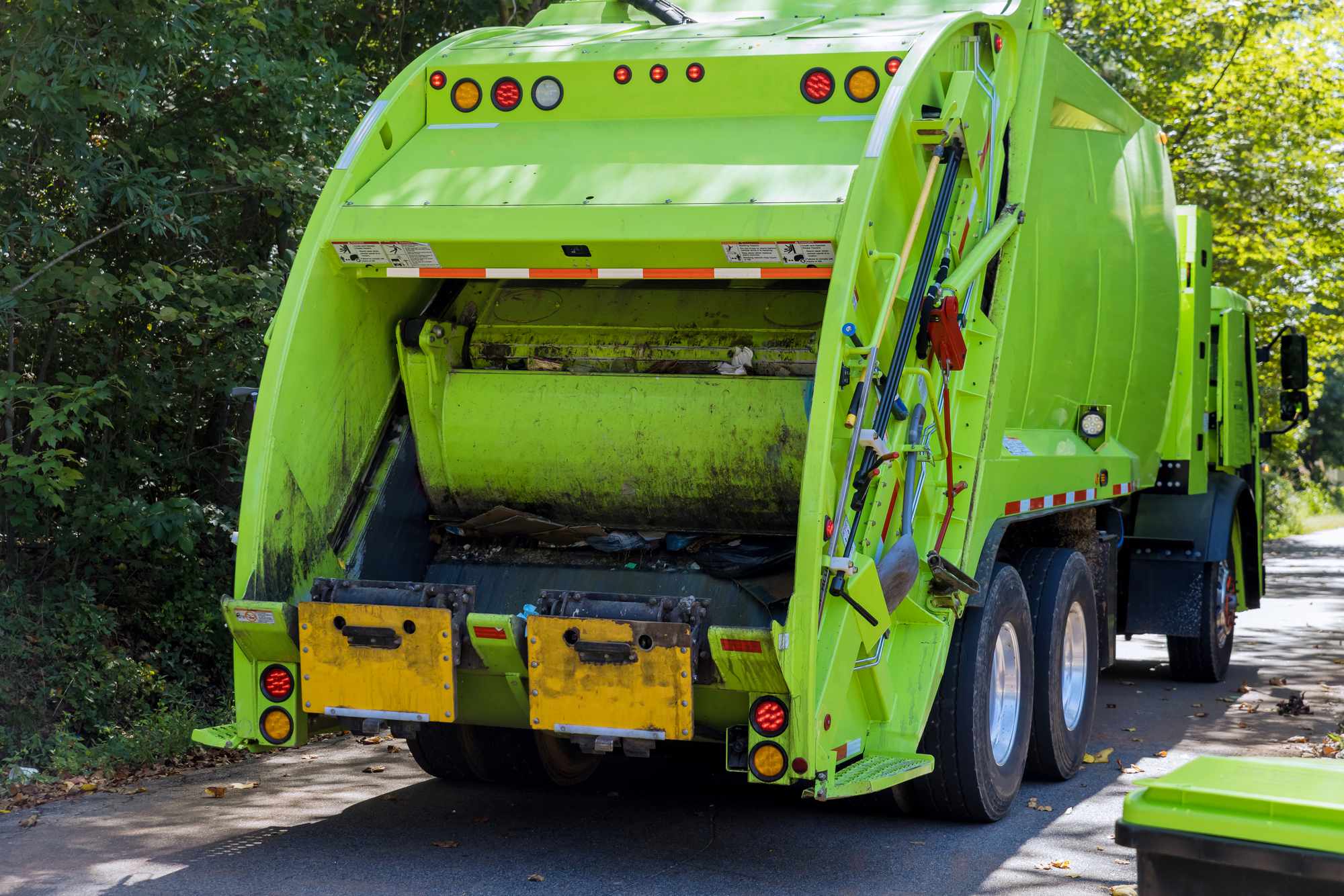 A green garbage truck from behind.