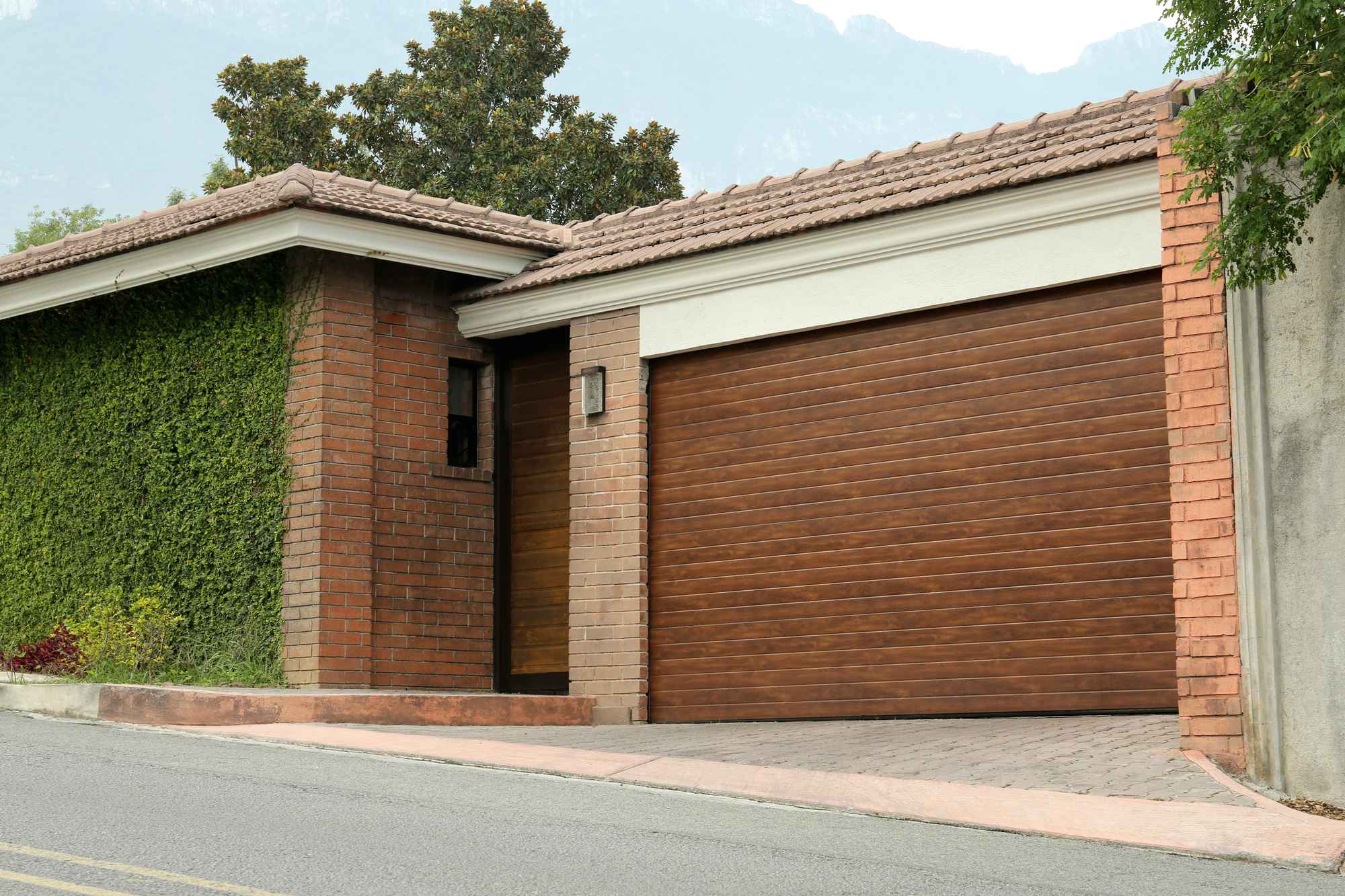 A wooden garage door on a short brick house.